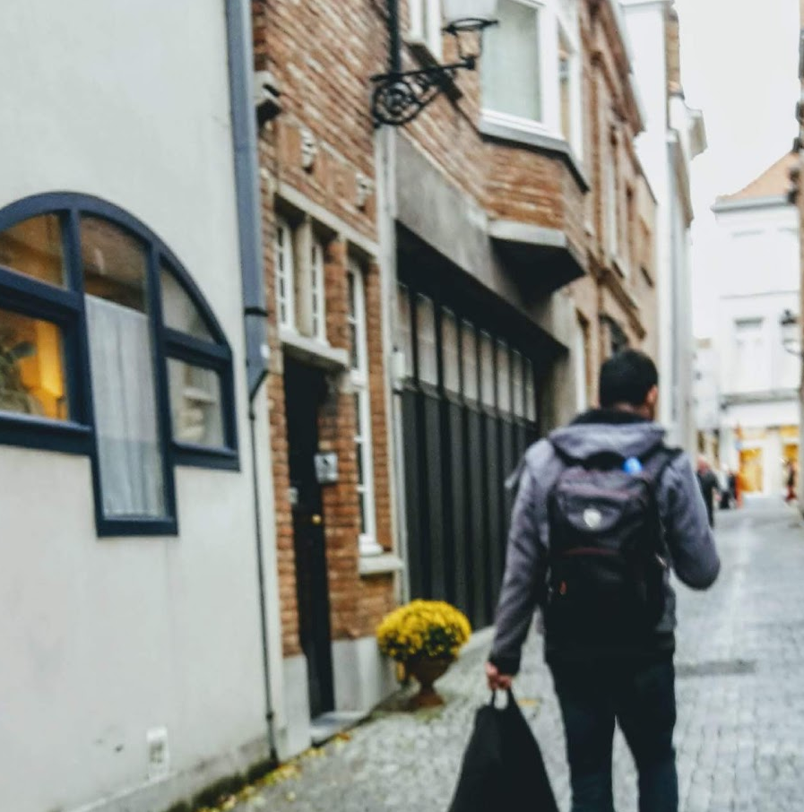 Viajante caminhando por rua histórica de paralelepípedos na Europa com mochila