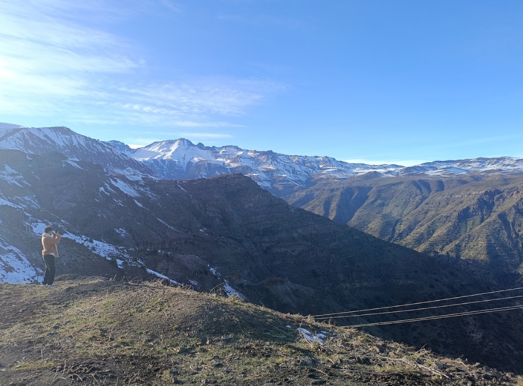 Viajante contemplando cordilheira com neve em viagem de aventura